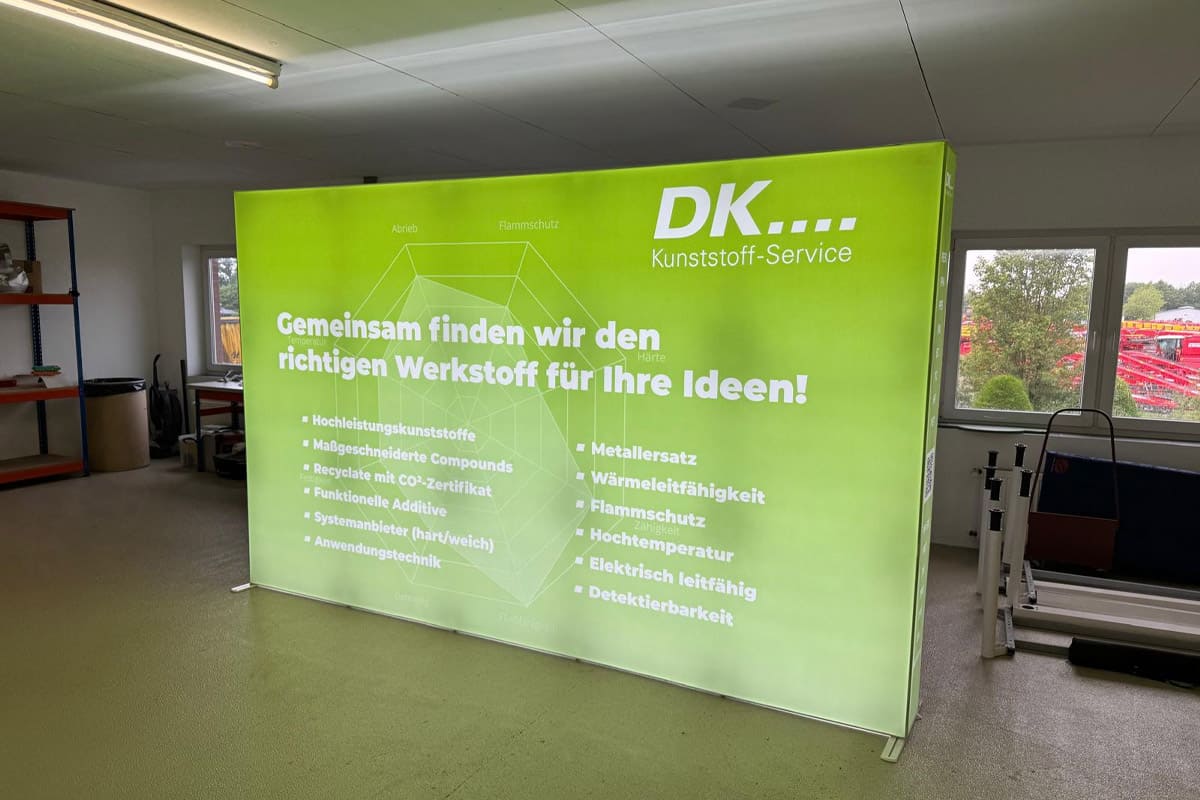 Referenz: beleuchtete LED-Messewand für DK Kunststoff-Service mit grünem Textildruck und großformatiger Werbegestaltung